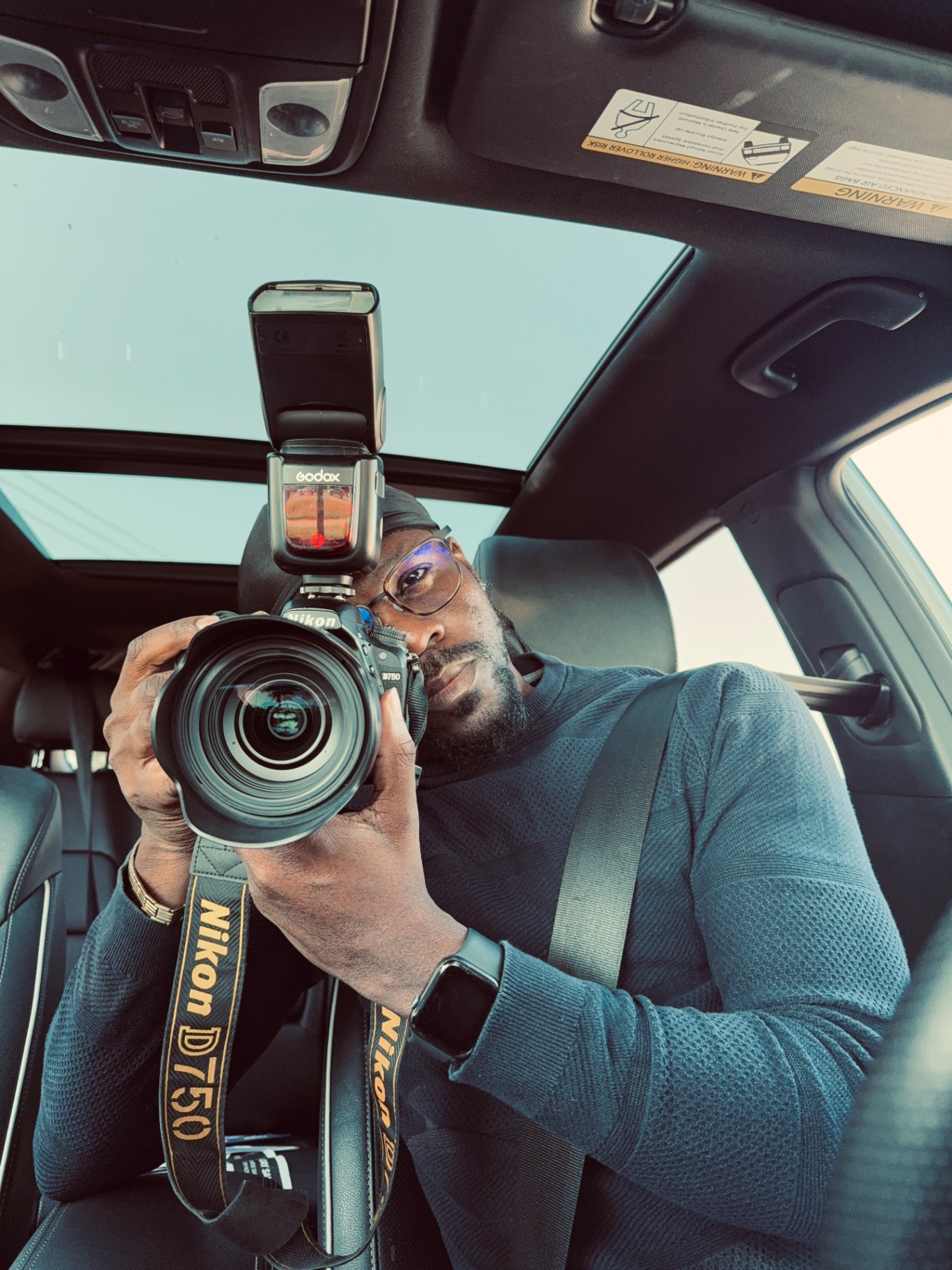 Self-portrait of the photographer behind Blu Pebble Studio holding a Nikon camera with a flash in his car